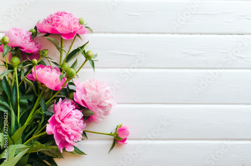 Pink peony flowers on white wooden table. womans day or wedding background. © mayanko