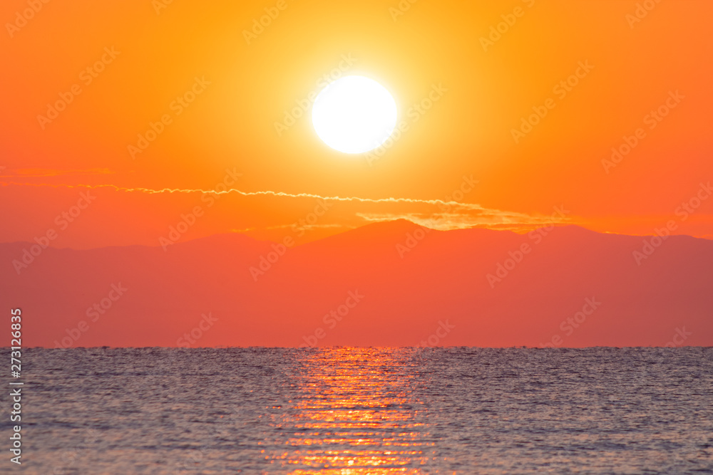 Sunrise / sunset at the sea with sun in the background