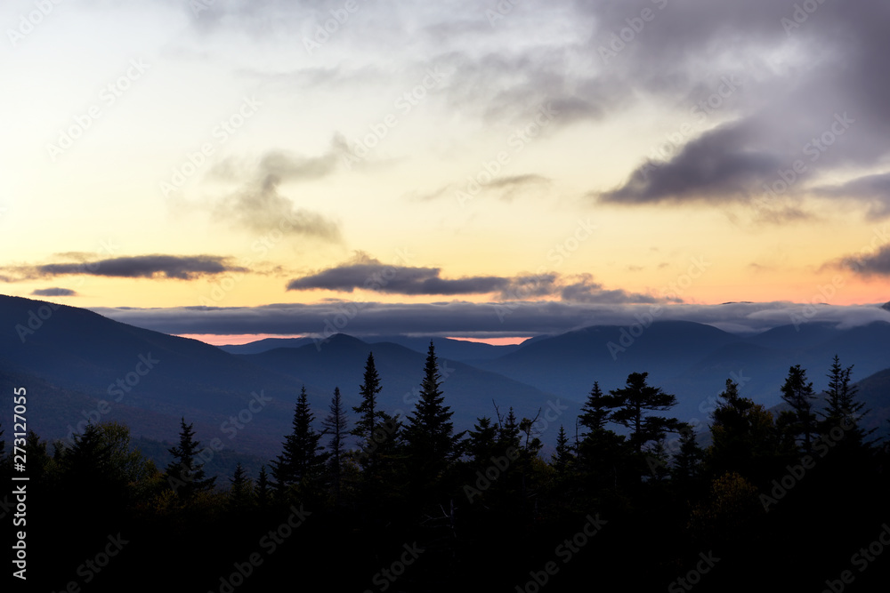 Wooded mountains and pink clouds on the peaks at sunset. White Mountain National Park. USA. New Hamshire.