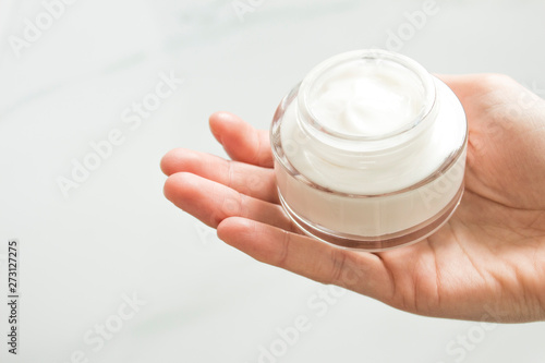 Beauty woman holding a glass jar of skin cream  on a white background. Female hands with cream. Closeup shot of hands applying moisturizer. Skin care, beauty and health.