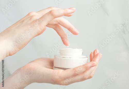 Beauty woman holding a glass jar of skin cream. Skin care concept. Woman taking care of her dry body. Moisturizing cream in female hands . Beauty treatment. Copy space.