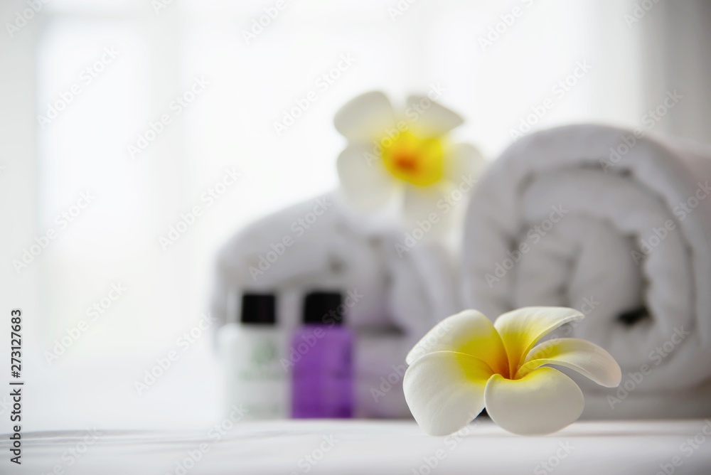 Hotel towel and shampoo and soap bath bottle set on white bed with plumeria flower decorated - relax vacation at the hotel resort concept Hotel towel and shampoo and soap bath bottle set on white bed with plumeria flower decorated - relax vacation at the hotel resort concept
