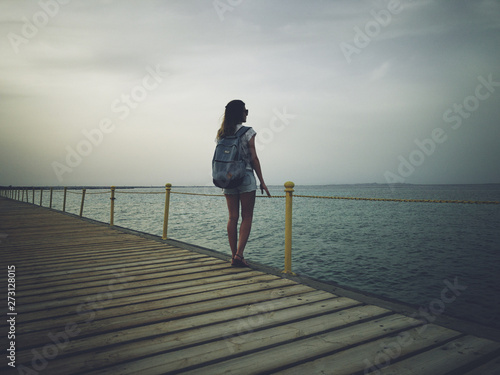 Single woman near the ocean / sea on a wooden pier.