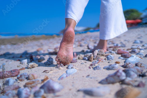 Close up low angle woman barefoot walking on beach with stone ground © etemwanich