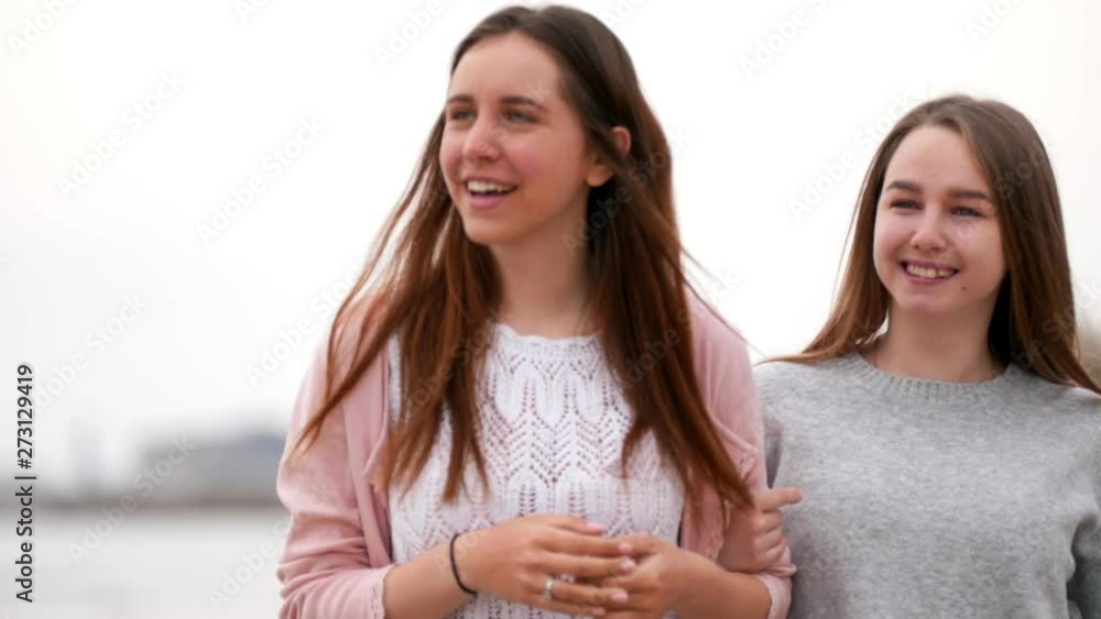 Two happy women are walking along the embankment in front of the sea Two happy women are walking along the embankment in front of the sea