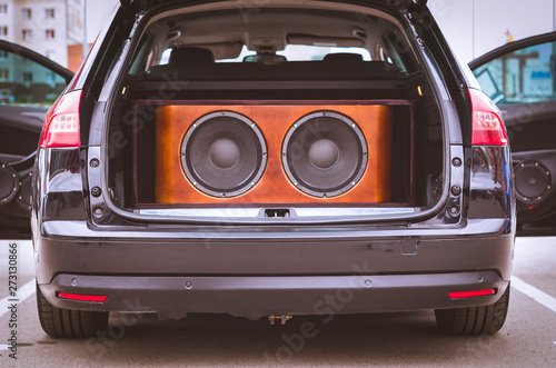 Rear View of a Car, Trunk and Front Doors Opened, With Installed Car Audio System, Sound Speakers and Subwoofer Sound Speakers in a Wooden Box.