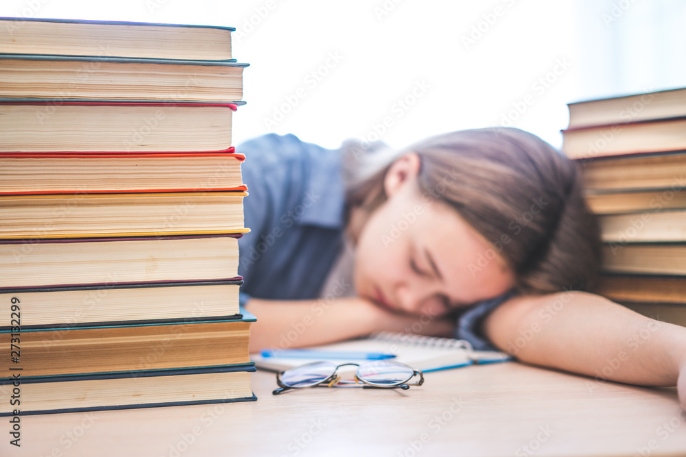Stressed college student tired of hard learning with books in exams tests preparation, overwhelmed high school teen girl exhausted with difficult studies or too much homework, cram concept. Stressed college student tired of hard learning with books in exams tests preparation, overwhelmed high school teen girl exhausted with difficult studies or too much homework, cram concept.