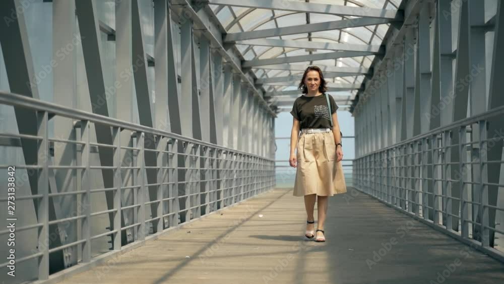A beautiful woman in a skirt is walking on a pedestrian bridge. Woman with a backpack. A beautiful woman in a skirt is walking on a pedestrian bridge. Woman with a backpack.