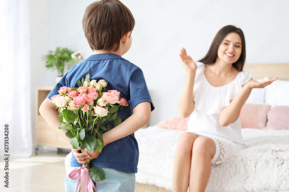 Little boy hiding bouquet of flowers for his mother behind back at home Little boy hiding bouquet of flowers for his mother behind back at home