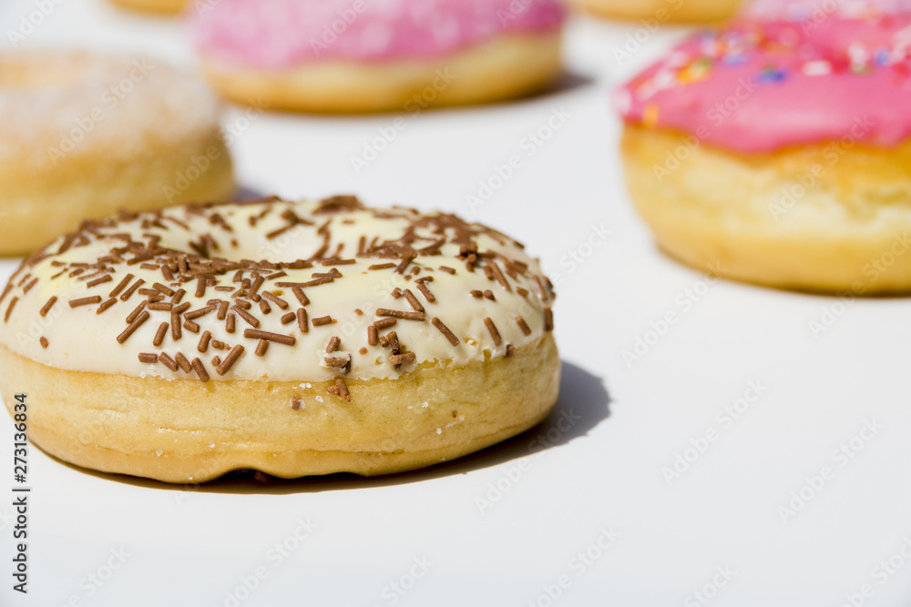 Delicious donuts with sprinkles on white backdrop