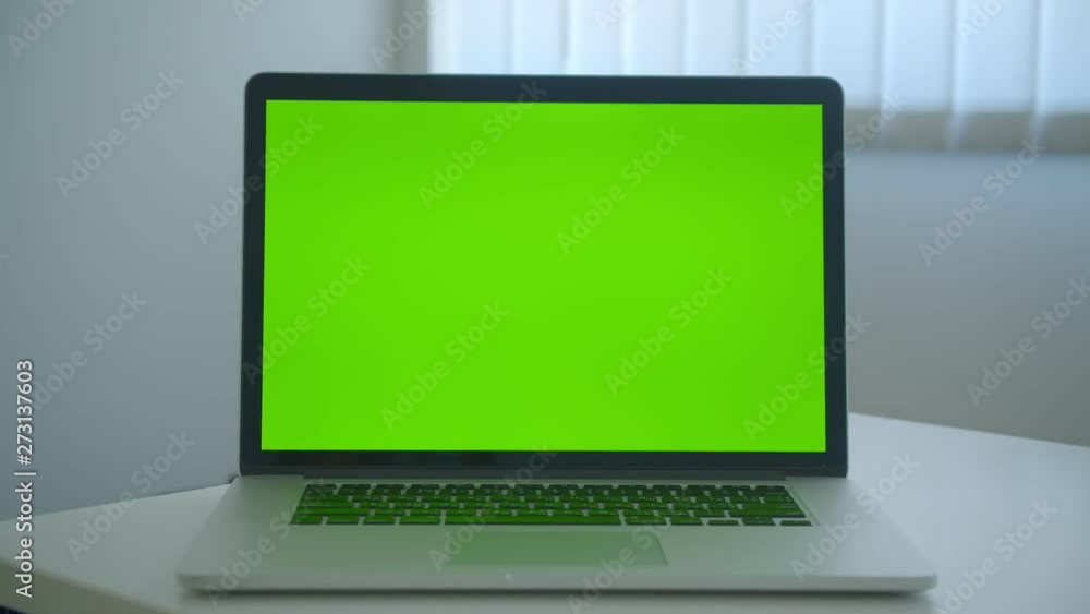 Closeup shoot of laptop with green chroma key screen laying on the table in the office indoors Closeup shoot of laptop with green chroma key screen laying on the table in the office indoors