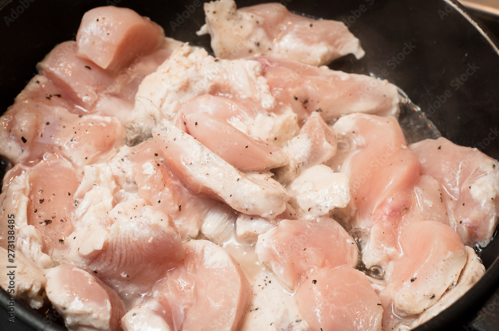 Half cooked chicken meat with spices in simmering sunflower oil in a pan. Half cooked chicken meat with spices in simmering sunflower oil in a pan.
