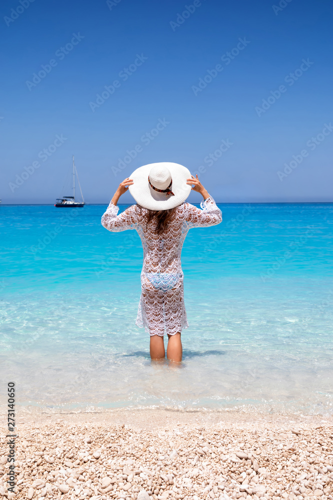 Attraktive Frau in weißem Sommerkleid genießt das leuchtend blaue Meer des Shipwreck Strandes auf Zakynthos, Ionische Inseln, Griechenland