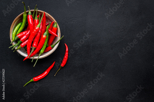 Cooking hot food with chilli pepper on black table background top view copy space