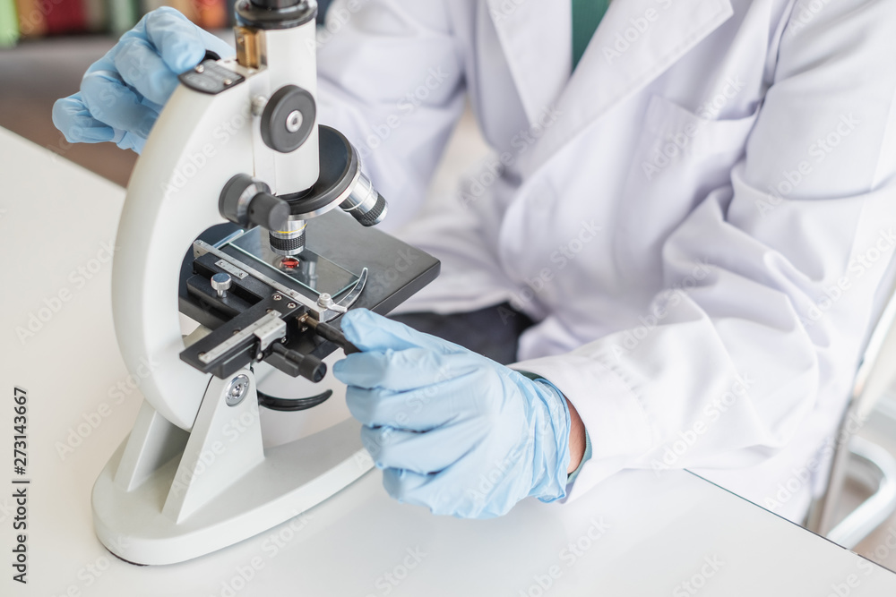A scientist hands working in laboratory with test tube microscope and solutions. A scientist hands working in laboratory with test tube microscope and solutions.