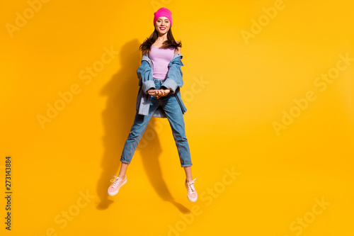 Full length body size photo beautiful amazing she her lady hands arms together jump high sporty day off mood cool look wear casual jeans denim jacket shoes pink hat isolated yellow bright background