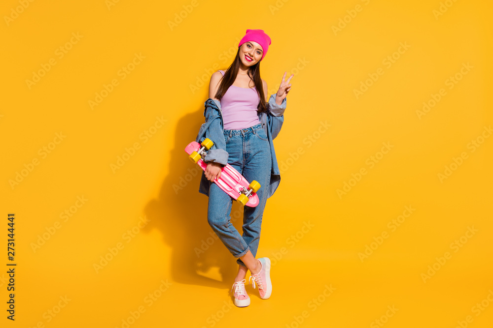 Full length body size photo beautiful she her lady amazing nice look hand arm skate board dangerous sport v-sign symbol wear casual jeans denim jacket shoes pink hat isolated yellow vivid background - obrazy, fototapety, plakaty 