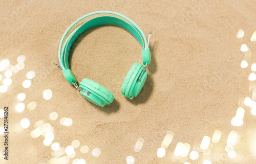 music, audio equipment and vacation concept - earphones on summer beach sand