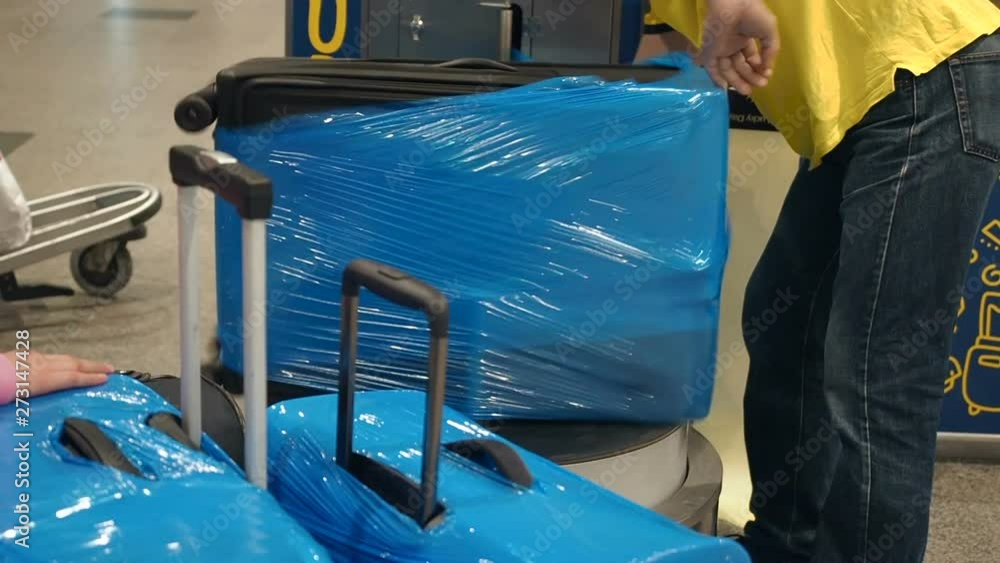 Luggage wrapping service at the airport, luggage is packed in cellophane cling film. Workers