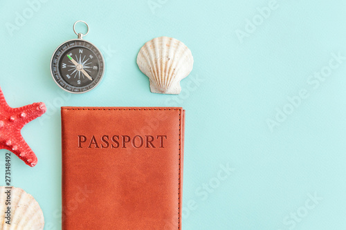 Vacation travel adventure trip concept. Minimal simple flat lay with passport compass and shell on blue pastel colourful trendy background. Tourist essentials Copy space