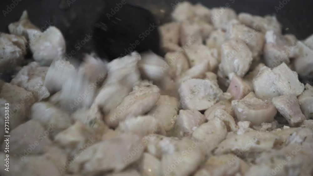 Chicken fillet slices are fried in a frying pan and stirred close-up Chicken fillet slices are fried in a frying pan and stirred close-up