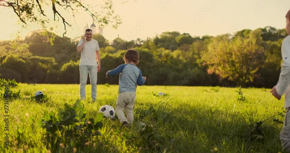 Young father with his little son playing football on football pitch. Young father with his little son playing football on football pitch.