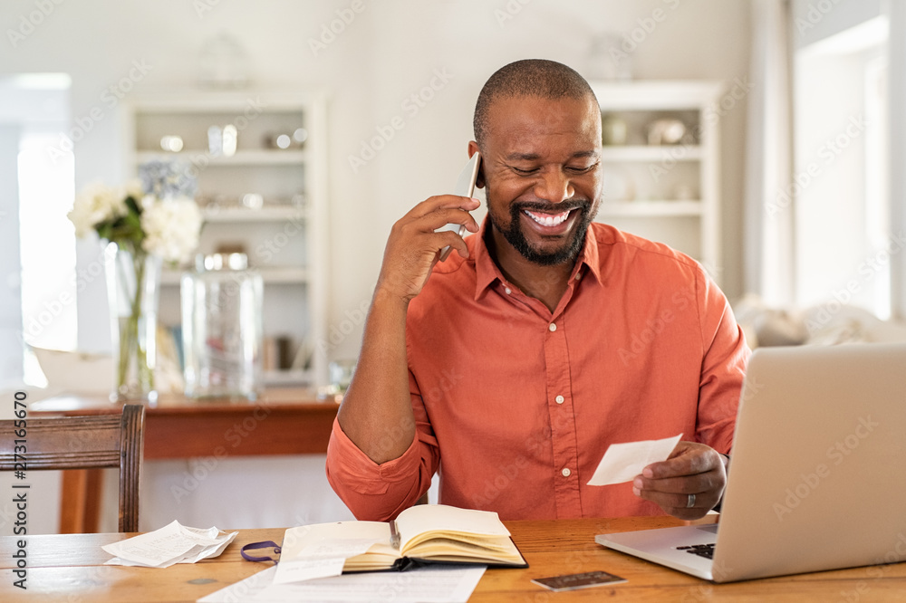 © Rido - Happy man reading invoice and talking on phone