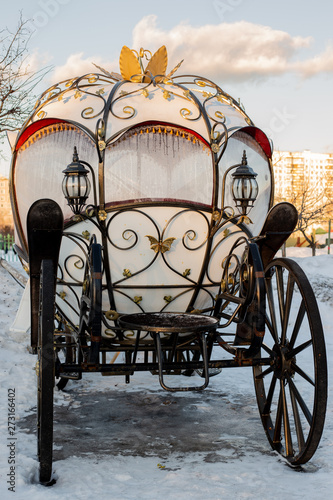 The white carriage with wrought iron elements is in the snow