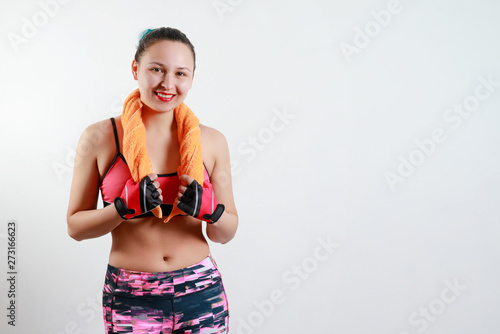 beautiful girl in sports clothes holds a towel with both hands around her neck. isolated on white