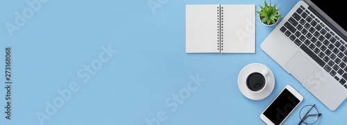 Business concept. Clean bright light blue office table desk, minimal style with laptop coffee and smart phone, copy space, top view, flat lay, mockup