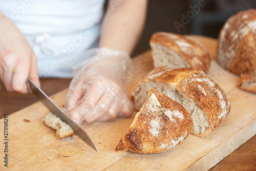 Woman cuts fresh bread on wooden background