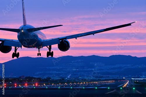 夕焼けの中で着陸する旅客機
