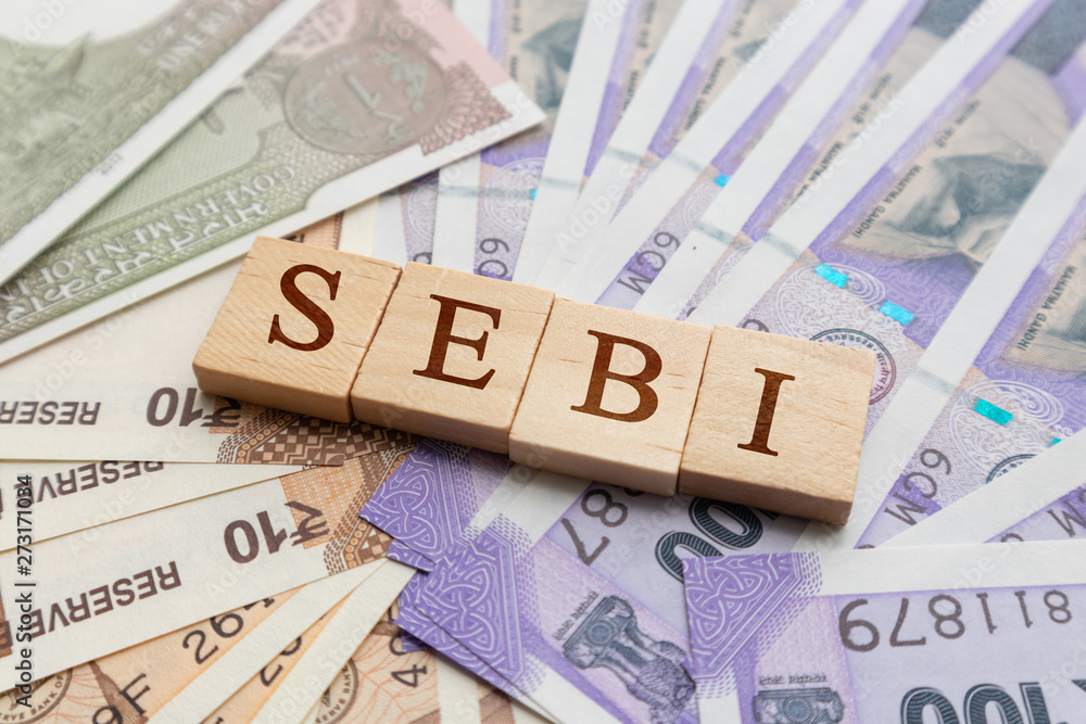 SEBI in wooden block letters on Indian Currency. SEBI in wooden block letters on Indian Currency.