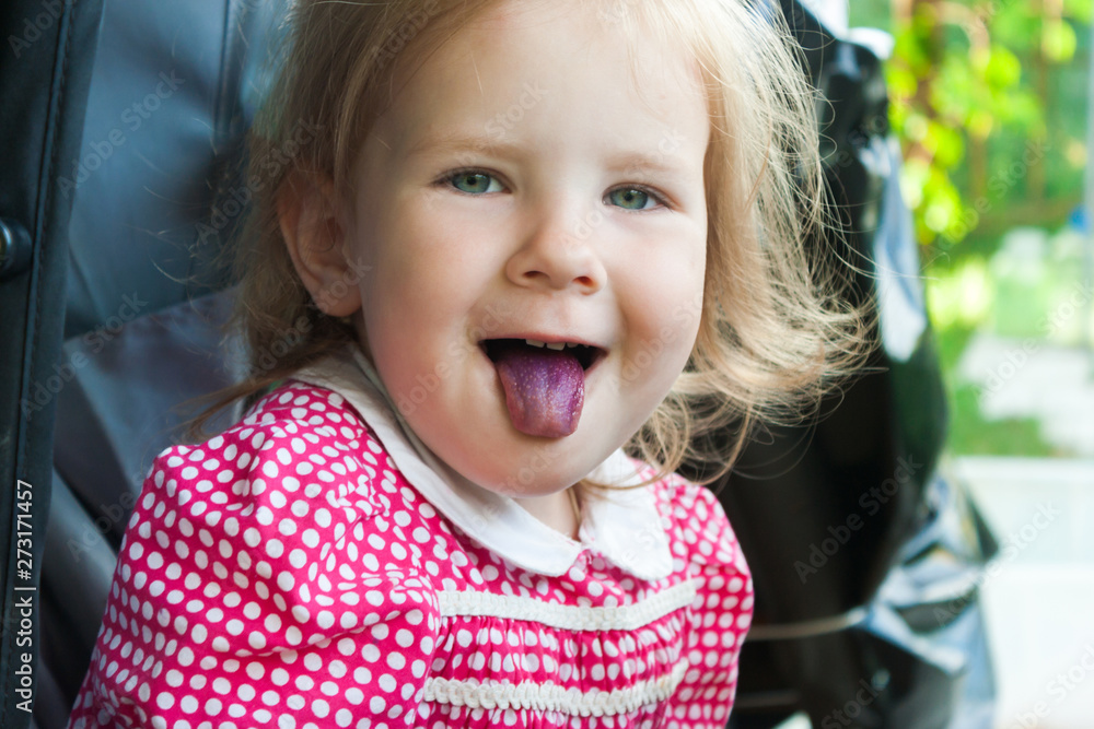 Little cute girl shows her blueberry-colored tongue. Little cute girl shows her blueberry-colored tongue.