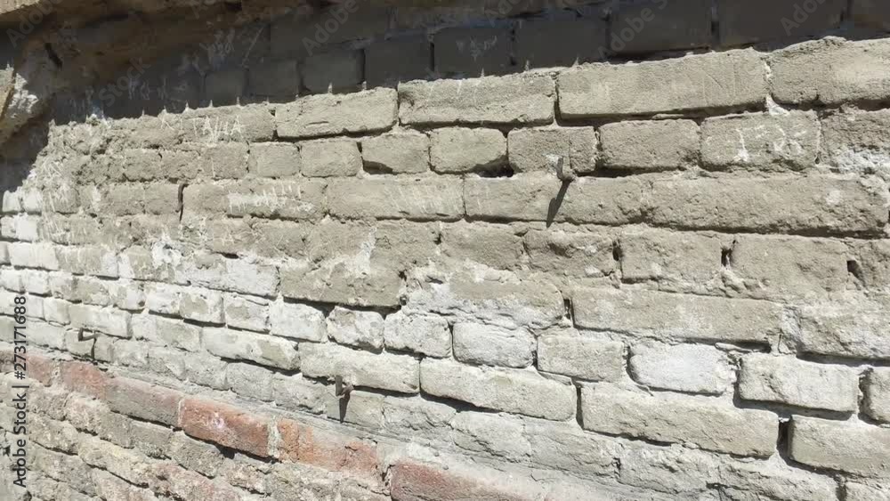 Bad foundations on old house cracked plaster facade wall with brick background under peeled cement, with motion 