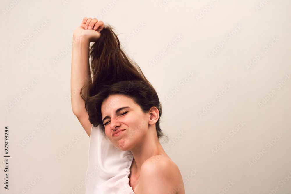 Close up photo portrait of young beautiful woman with freckles which pulls her hair as a joke. Funny face on gray background. Nursing hair care Close up photo portrait of young beautiful woman with freckles which pulls her hair as a joke. Funny face on gray background. Nursing hair care