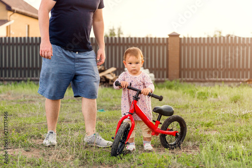 Young father spend time with Cute little one years old toddler girl child and balance bike, father's day