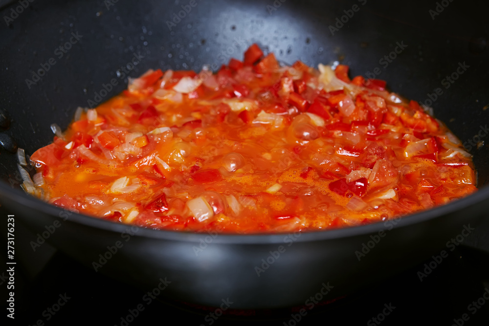 red sauce of vegetables in a deep black frying pan. Close-up red sauce of vegetables in a deep black frying pan. Close-up