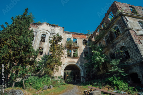 Ruined overgrown hospital in ghost mining town Akarmara, consequences of war in Abkhazia, green post-apocalyptic concept photo