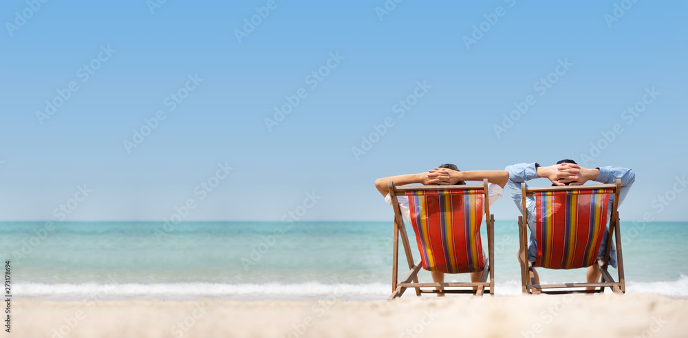 Couple relaxing on chair beach over sea background. - obrazy, fototapety, plakaty 