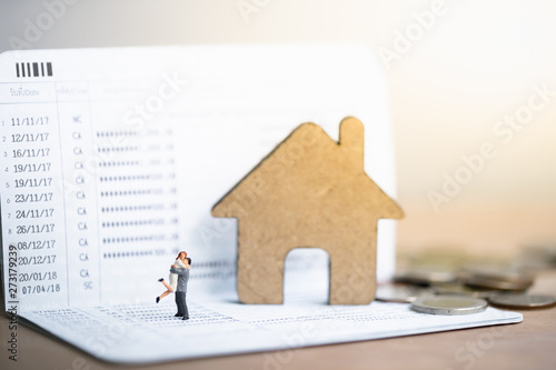 House model and small couple figures in love standing on bank passbook. Love and Valentine's day concepts. family finance concept. Saving money for get marriage.