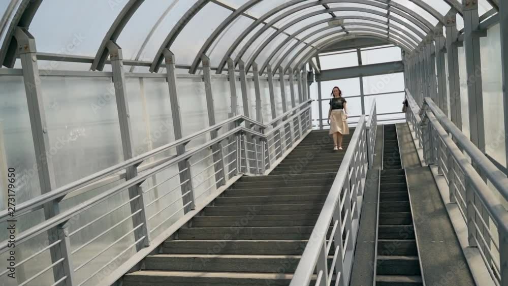 A woman walks down the steps from a footbridge. A woman walks down the steps from a footbridge.