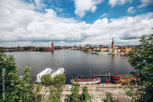 Scenic summer panorama of the Old Town (Gamla Stan) architecture in Stockholm, Sweden. view from Monteliusvagen hill on island Riddarholm and tower of church. Lake Malaren with blue sky, white clouds. © Stanislav
