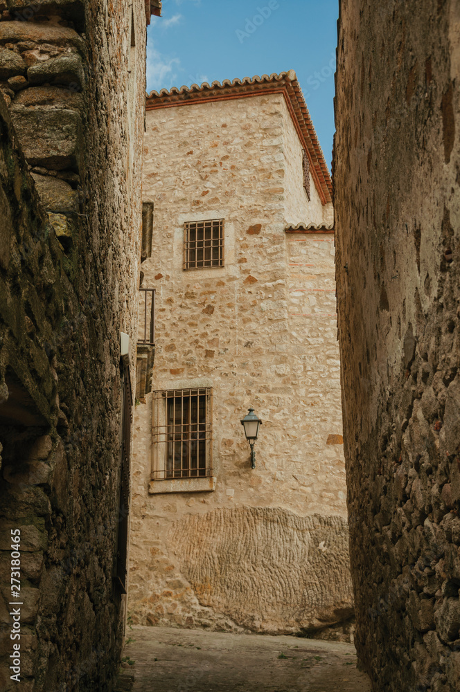 Alley with old stone buildings and public lamp at Trujillo