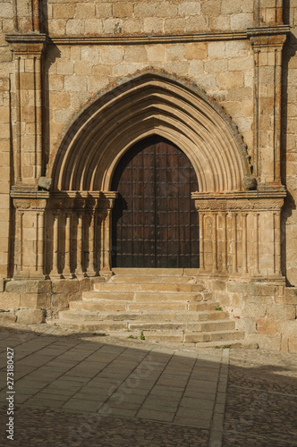 Wooden door with labored medieval stone arches and steps at Trujillo