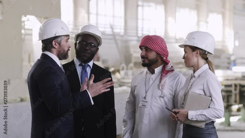 Caucasian factory worker sharing experience with foreign guests at building manufactory Caucasian factory worker sharing experience with foreign guests at building manufactory