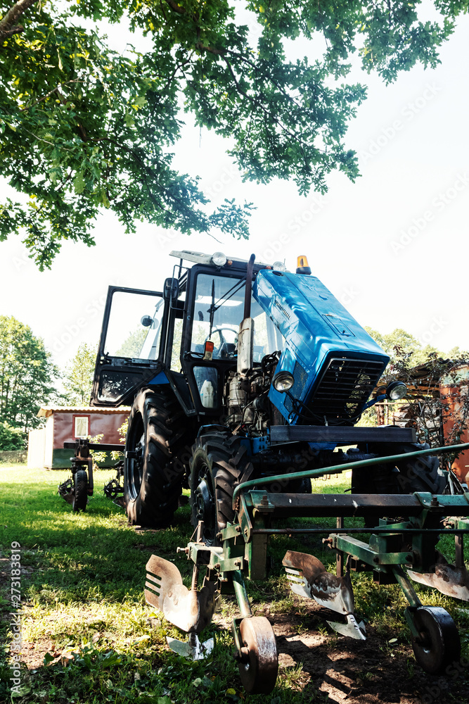 Agriculture, tractor with iron plow cultivator. Tractor in yard of farmer. Agriculture, tractor with iron plow cultivator. Tractor in yard of farmer.