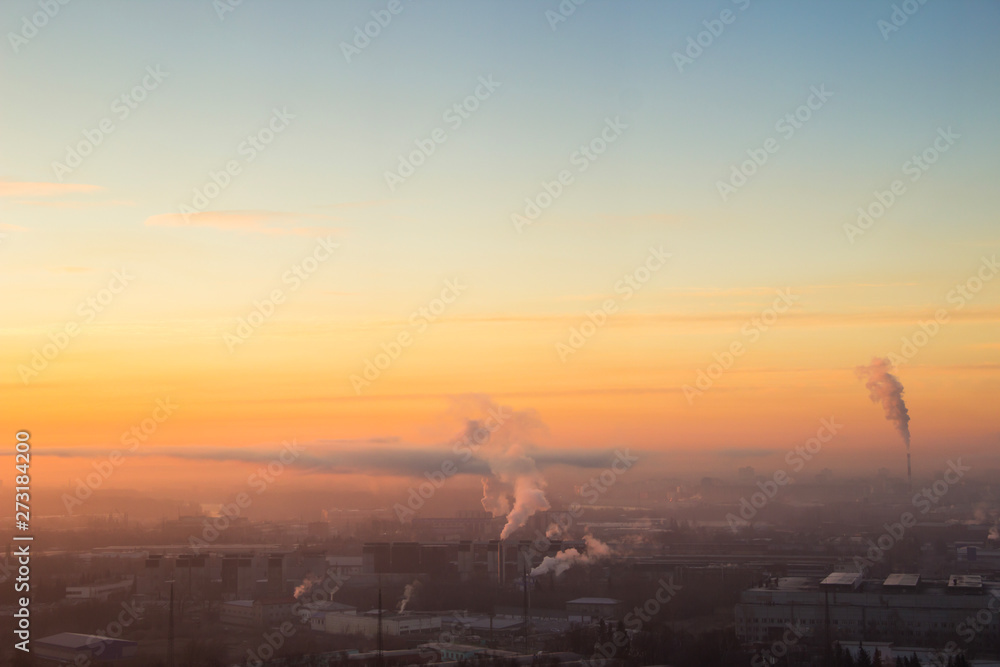 Fototapeta premium Sunrise over factory at the industrial area. Orange light rays comes through morning fog and smoke from pipes. Power plant