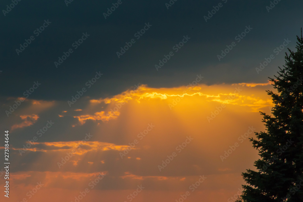 Orange sun beams through the clouds. Dramatic sky on sunset