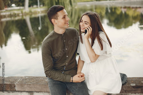 Cute couple in a city. Lady in a white dress. Boy in a green shirt. Pair sitting near river